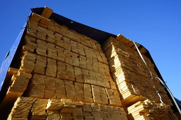 Gestapelte Kanthölzer im Lager einer Tischlerei und Schreinerei für Bau und Handwerk mit blauer...