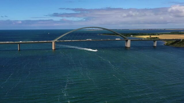 Drone shot, drone video, drone flight, aerial view, flight over the strait near Fehmarn Island, Fehmarnsund Bridge, flowing traffic, truck, car, train, wide view over the island, fast motorboat on