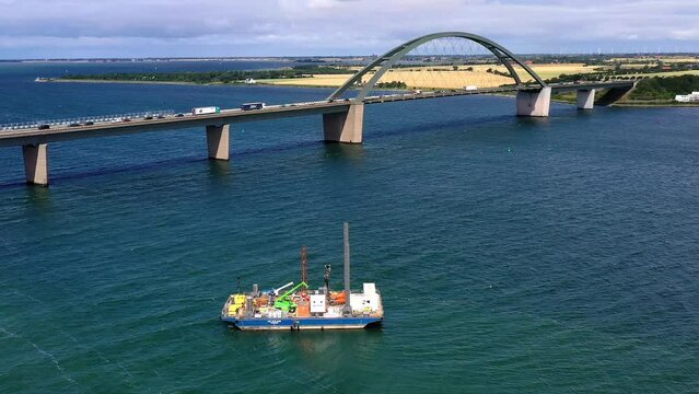 Drone shot, drone video, drone flight, aerial view, flight over the strait near Fehmarn Island, Fehmarnsund Bridge, flowing traffic, truck, car, train, far view over the island, work ship, supply