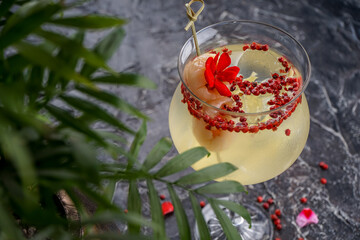 cocktail in a glass on a stem decorated with a red flower macro photo
