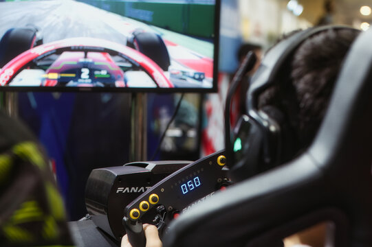 Ta Qali, Malta - 05 November 2022: Unrecognizable Person Playing A Racing Simulator Video Game Using A Gaming Steering Wheel At A Gamer Convention