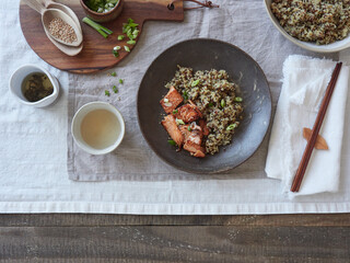 quinoa and salmon dish on the table on linen tablecloth, wooden chopsticks and utensils, tea served in ceramic.