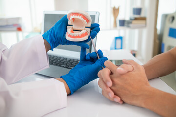 Dentists recommend ways treat problem teeth and dentists also advise patients know take care of their teeth after treatment is completed. Dentist holding dentures in hand and talking to patient