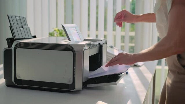 Hands of female secretary trying to fix broken printer on desk working at modern office