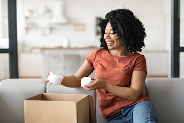 Beauty Shopping. Excited Black Female Unpacking Box With Skincare Products At Home
