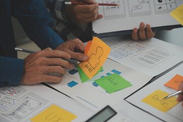 Close up ux developer and ui designer brainstorming about mobile app interface wireframe design on...