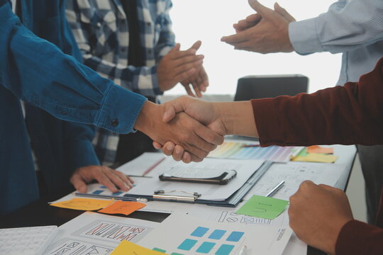 Close up ux developer and ui designer brainstorming about mobile app interface wireframe design on table with customer breif and color code at modern office.Creative digital development agency