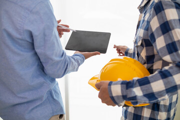 Construction engineers discuss and exchange ideas with architects to improve house plans to meet...