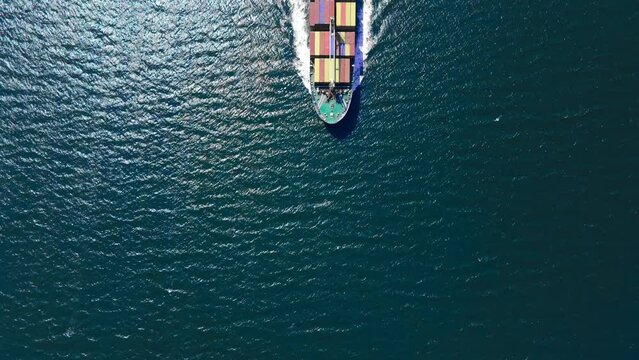 Aerial footage of large container ship cruising in open sea, top down view