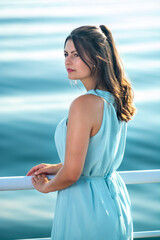 attractive woman stands at the railing and looks at the sea