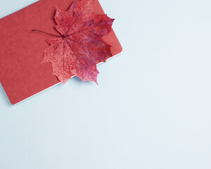 Plans for fall, new academic year, work after summer holidays. Notepad and maple leaf autumn symbol on blue background. Flat lay, copy space, top view
