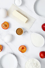 Ingredients for making classic cake pie with plums on white background. Concept homemade food, seasonal pastries. Top view