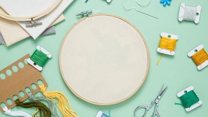 Embroidery set fot stitching. Beige cotton cloth in embroidery hoop on green background with...