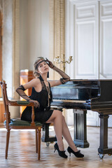 Fototapeta na wymiar A girl in a twenties outfit sits on a chair at an antique black piano
