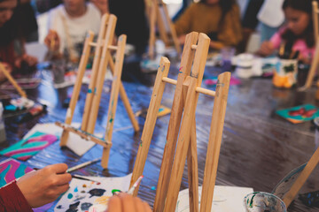 Process of painting, group class of young talented kids students with painting easels, and canvases...