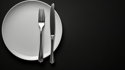 A white plate with a fork and knife on a black background