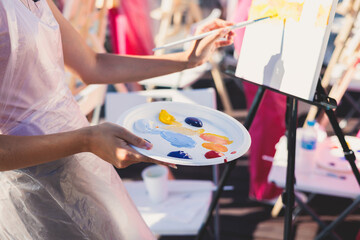 Process of drawing, group class of talented students with painting easels and canvases during lesson of watercolour painting outdoors, drawing class for adult artists in art school