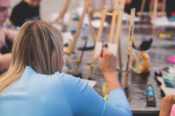 Obraz premium Process of drawing, group class of talented students with painting easels and canvases during lesson of watercolour painting outdoors, drawing class for adult artists in art school