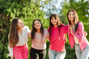 Group of smiling confident women with pink ribbon on t shirts looking at camera