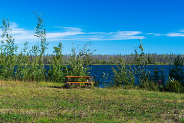 Fototapeta premium A picnic table sits next to a beautiful blue lake, Northwest Territories, Canada