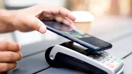 Hands using an NFC mobile phone to make a contactless payment in a store, illustrating near field communication technology