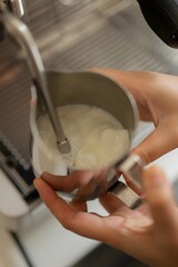 Barista is using high pressure steam operated milk  to milk foam