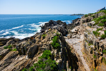 Giants Stairs trail on Bailey Island with views of Casco Bay. Photos of the rocky shoreline taken in summer on a clear blue day.