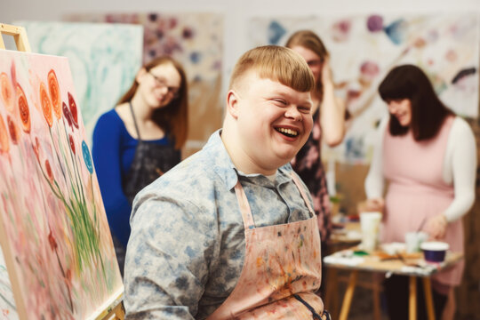 Young smiling man with Down syndrome on art workshop with a group of students, learning a new skill. Social integration concept.