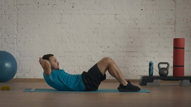 Closeup shot. Man fitness coach in sportswear doing classic abs crunches exercise for online class at the home studio.