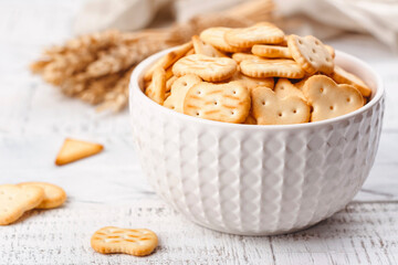 Crackers over the keyboard day, 28 august. Dry salty cracker cookies in white bowl on wooden table