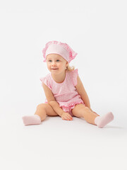 Surprise, a game, a girl of 2 years old in a pink dress and socks sits on the floor and looks at something attentively with interest.