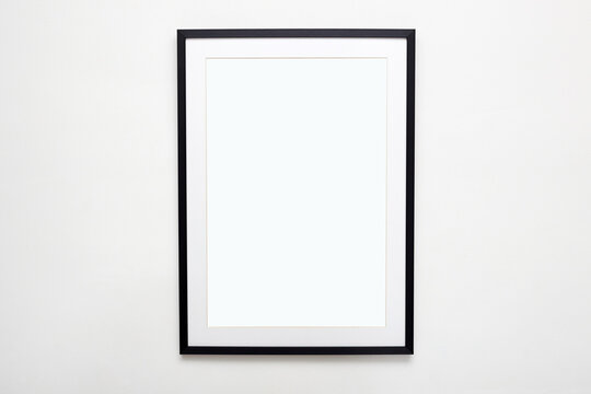 big black picture frame on white wall. Stylish photoframe with passe-partout