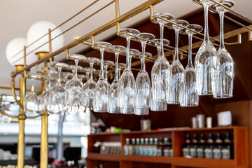 Clean wine glasses hanging upside down above a bar rack in restaurant - 638059496