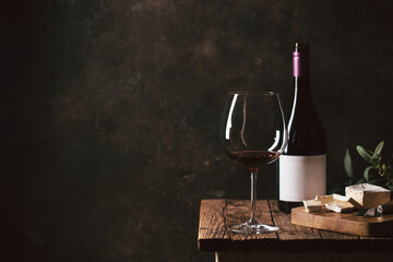 Glass of red wine with bottle against rustic dark wooden background