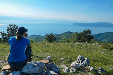 A woman sitting on top of Vojak and enjoying the panoramic view on Mediterranean Sea. The mountain...