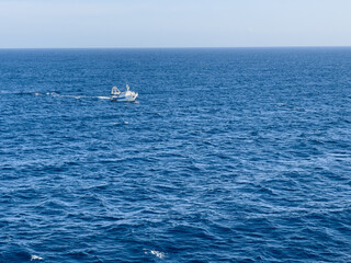 Small, fishing boat at open sea with waves.