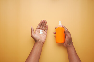  young men using sunscreen cream on orange color background 