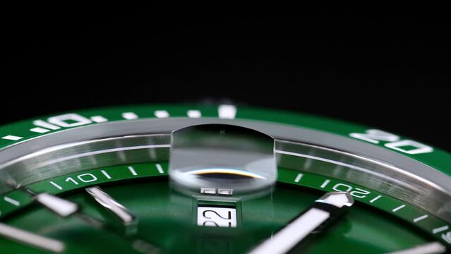 Stylish Luxury Man Wrist Watch With Moving Hand And Multiple Dials. Men's watch in metal with sapphire crystal. Closeup view of rotating watch, running second arrow. green dial. Cyclops watch