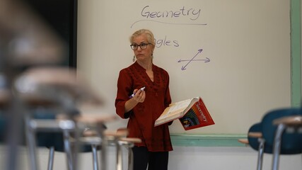 Closeup view of woman teacher using an interactive whiteboard blackboard in an empty classroom teaching geometry math.