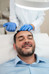 Handsome middle age man receiving advanced Platelet Rich Plasma PRP treatment against hair loss....