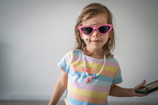 caucasian girl toddler with painted color draws and stains on face