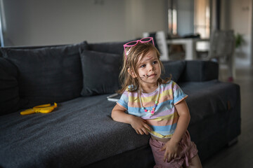 caucasian girl toddler with painted color draws and stains on face