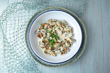 Mussels in creamy sauce on a blue background. Mediterranean Kitchen. Sea mood menu.