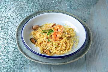 Spaghetti with seafood and parmesan on a blue background. Mediterranean Kitchen. Sea mood menu.