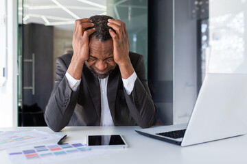 African american mature adult businessman upset in depression at workplace, senior man working in middle of office, unhappy with results of financial achievement banker investor