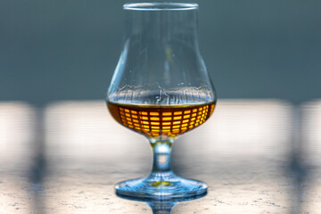 Single malt scotch whiskey in glencairn tasting glass with window reflection in liquid
