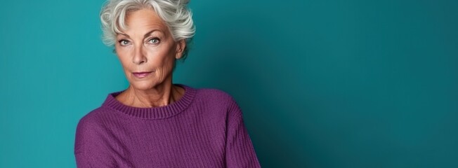 70 years old model posing for the colors of life. Aging woman standing in front a wall. Turquoise, teal, purple, grey color scheme. Grey haired baby boomer, healthy, happy, enjoying the fall of life.