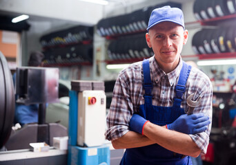 Professional auto mechanic in workwear posing on his workplace in workshop