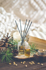 Assortment of natural Christmas essential oils in small bottles. Candles, branches of fir tree, home aroma diffuser. Aromatherapy, cozy atmosphere, holiday festive mood. Close up macro, wooden table