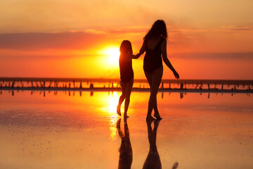 Happy family summer travel holiday. Silhouette of mom with child daughter holding hands walking...